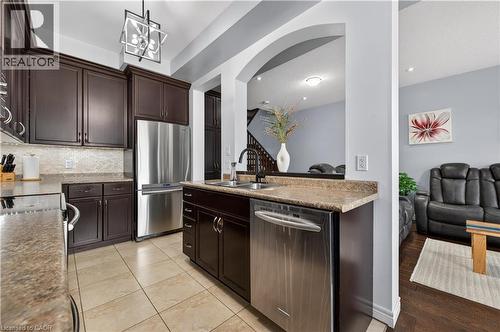 Kitchen featuring dark wood cabinetry, stainless steel appliances, speckled countertops, and a tiled backsplash - 88 Highgate Drive, Hamilton, ON 