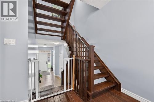 Hardwood staircase with traditional balusters, wood-finish flooring, and light gray wall paint - 88 Highgate Drive, Hamilton, ON 