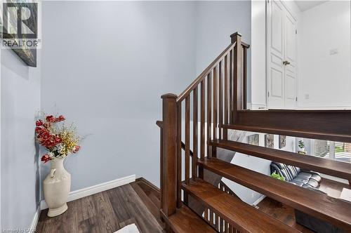 Wood-finish flooring, dark wood staircase with balusters, and white paneled doors - 88 Highgate Drive, Hamilton, ON 