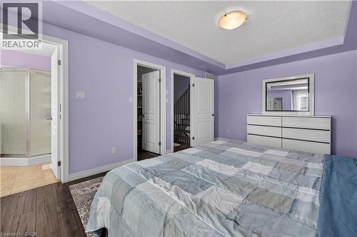 Wood-finish flooring, tray ceiling, recessed lighting, white trim, and a glass-enclosed shower - 88 Highgate Drive, Hamilton, ON 
