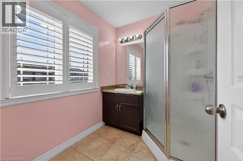 Bathroom featuring a dark wood-finish vanity with a surface-mounted sink, a glass-enclosed shower, and plantation shutters - 88 Highgate Drive, Hamilton, ON 