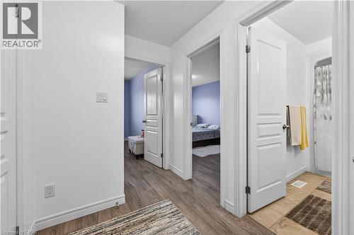 White interior walls, wood-finish flooring, white panel doors, and tiled flooring in the bathroom - 88 Highgate Drive, Hamilton, ON 