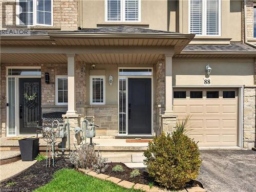 Brick and stone facade with a covered entry, single garage door, and decorative exterior lighting - 88 Highgate Drive, Hamilton, ON 