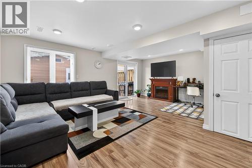Recessed lighting, wood-finish flooring, white paneled door, sliding glass door, and a built-in electric fireplace with a wood mantel - 88 Highgate Drive, Hamilton, ON 