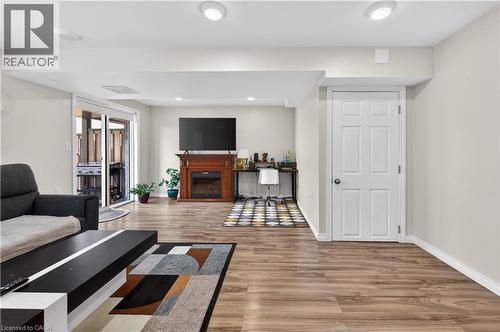 Recessed lighting, wood-finish flooring, white paneled door, sliding glass doors, built-in electric fireplace with wood surround - 88 Highgate Drive, Hamilton, ON 