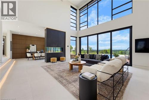 Soaring ceilings, expansive window walls, sleek built-in fireplace, wood-finish accent wall, and light-toned flooring - 5709 Forth Line, Hillsburg, ON 