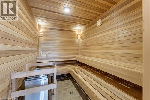 Spa-inspired sauna featuring horizontal wood-plank walls and ceiling, recessed lighting, wall-mounted sconces, tiered wood benches with contrasting finish, and radiant floor heating elements visible t - 5709 Forth Line, Hillsburg, ON 