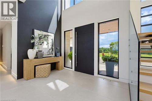 Modern foyer showcasing a dramatic deep navy accent wall, light-filled spaces with floor-to-ceiling windows, polished concrete flooring, and direct access to an expansive outdoor terrace - 5709 Forth Line, Hillsburg, ON 