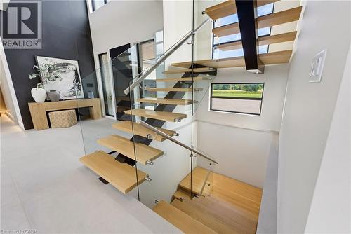 Modern staircase featuring floating wood-finish treads, sleek metal railings with glass panels, and a skylight above flooding the space with natural light - 5709 Forth Line, Hillsburg, ON 