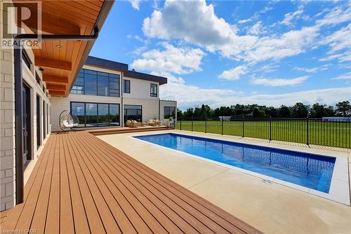Expansive wood-finish deck, rectangular swimming pool, concrete pool surround, and a fenced perimeter - 5709 Forth Line, Hillsburg, ON 