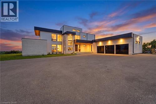Modern architectural exterior with expansive glazing, a multi-car garage, and a large paved driveway - 5709 Forth Line, Hillsburg, ON 