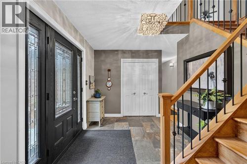 Entryway featuring a decorative transom, leaded glass sidelights, tiled flooring, wood staircase with wrought iron balusters, and a contemporary ceiling light fixture - 2023 Latimer Crescent, Greater Sudbury, ON 