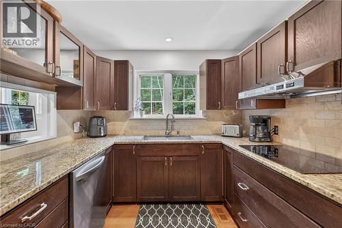 U-shaped kitchen with wood-finish cabinetry, granite-s countertops, and  tile backsplash - 2023 Latimer Crescent, Greater Sudbury, ON 