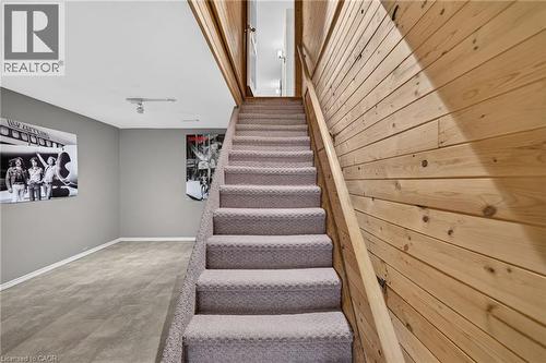 Carpeted staircase with a wood-paneled wall, leading to a carpeted room with light gray walls and track lighting - 2023 Latimer Crescent, Greater Sudbury, ON 