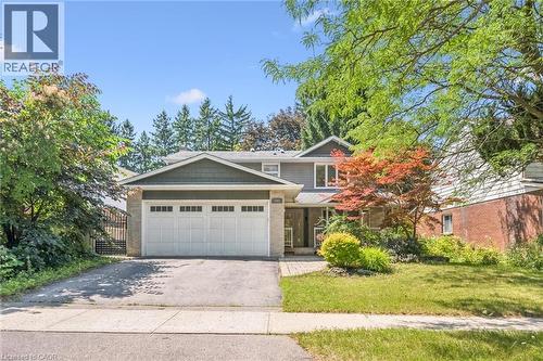 Two-story home featuring a two-car garage, paved driveway, mature landscaping, and a brick and siding exterior - 345 Beechlawn Drive, Waterloo, ON 