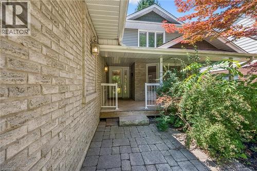 Brick exterior with a covered porch featuring white railings, dual entry doors, and a paver pathway - 345 Beechlawn Drive, Waterloo, ON 
