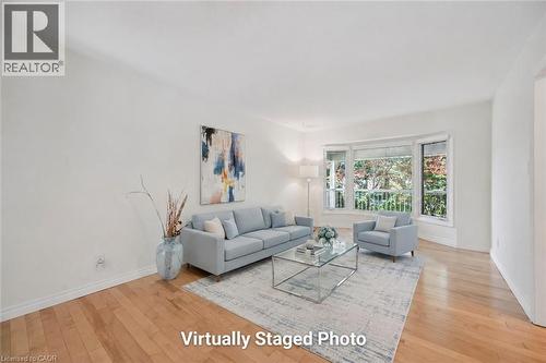 Bright, light-filled living room showcasing hardwood flooring, expansive glass doors and windows with natural outdoor views, neutral wall finishes, and an open floor plan ideal for entertaining - 345 Beechlawn Drive, Waterloo, ON 
