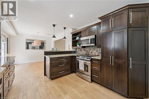 Gourmet kitchen featuring rich wood cabinetry with ample storage, stainless steel appliances including a professional-style range, quartz countertops, tile backsplash, and a substantial island with se - 345 Beechlawn Drive, Waterloo, ON 