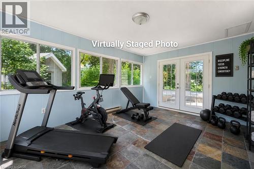 Flexible bonus room with slate tile flooring, light blue paneling, multiple windows, and French doors - 345 Beechlawn Drive, Waterloo, ON 