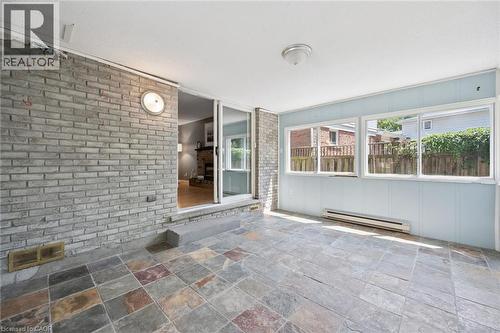 Sunlit covered patio with slate-finish tile flooring and expansive glass sliding doors opening to the residence - 345 Beechlawn Drive, Waterloo, ON 