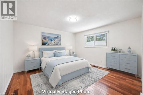 Spacious bedroom showcasing hardwood flooring, soft blue painted cabinetry, and ample natural light from dual windows - 345 Beechlawn Drive, Waterloo, ON 