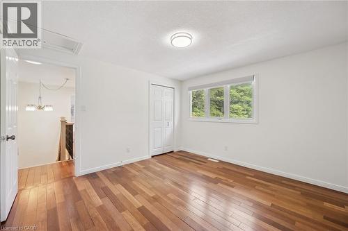 Spacious room featuring wood-finish flooring, white walls, and a three-pane window with natural light - 345 Beechlawn Drive, Waterloo, ON 