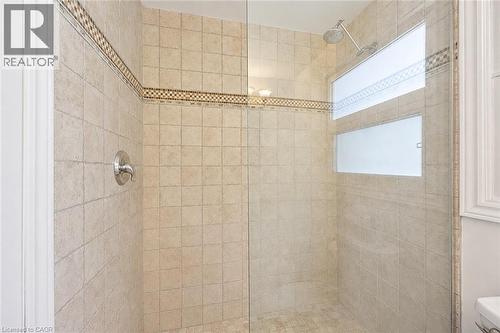 Glass-enclosed shower with full-height neutral-toned tile walls, decorative mosaic accent banding, and a rainfall showerhead - 345 Beechlawn Drive, Waterloo, ON 