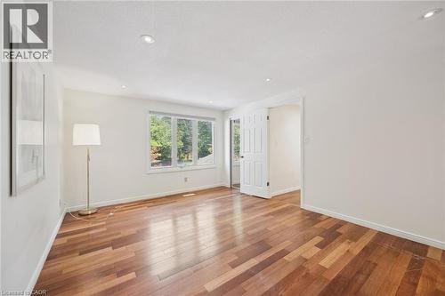 Spacious room featuring wood-finish flooring, recessed lighting, and a large multi-pane window - 345 Beechlawn Drive, Waterloo, ON 