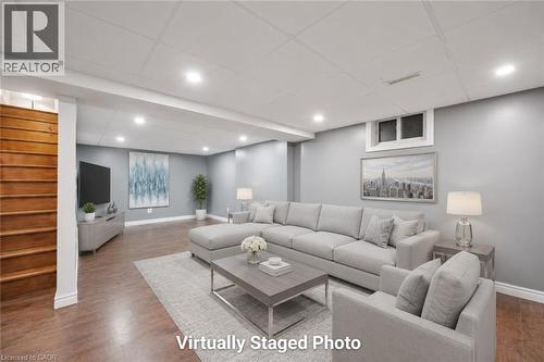 Spacious living area featuring wood-finish flooring, recessed lighting, and a white grid-patterned ceiling - 345 Beechlawn Drive, Waterloo, ON 