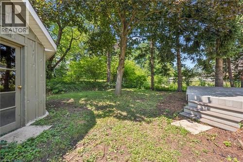 Expansive rear yard featuring mature trees, a concrete paver patio, and a storage structure with board and batten siding - 345 Beechlawn Drive, Waterloo, ON 