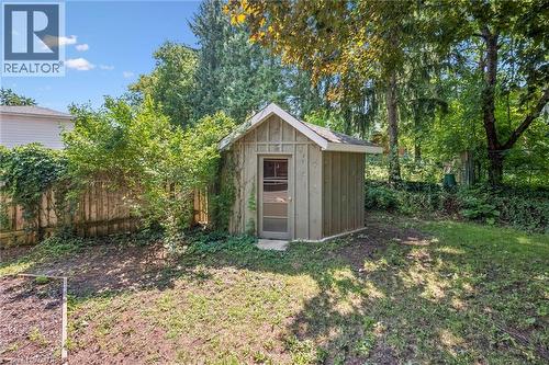 Backyard storage shed featuring vertical wood siding, a gabled roofline, and a full-light entry door - 345 Beechlawn Drive, Waterloo, ON 
