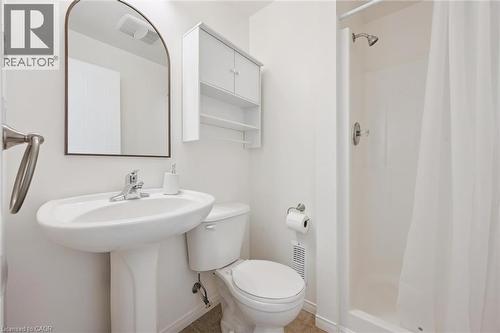 Pedestal sink with chrome fixtures, arched mirror, wall-mounted storage cabinet, and a shower with a white curtain - 151 Clairfields Drive Unit# 3, Guelph, ON 