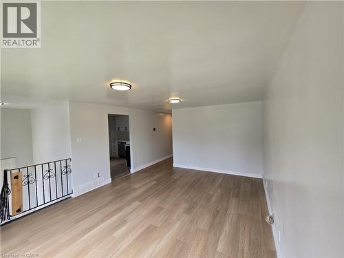 Wood-finish flooring throughout, complemented by a decorative iron railing and recessed lighting fixtures - 99 Cluthe Crescent, Kitchener, ON 