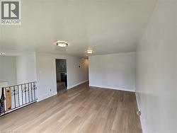 Wood-finish flooring throughout, complemented by a decorative iron railing and recessed lighting fixtures - 