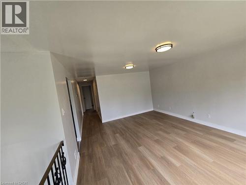 Spacious room featuring wood-finish flooring, light-colored walls, and two flush-mount ceiling lights - 99 Cluthe Crescent, Kitchener, ON 
