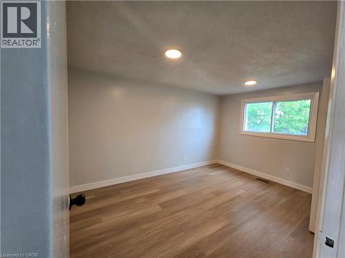 Recessed lighting illuminates the room, featuring wood-finish flooring and a white-framed window - 99 Cluthe Crescent, Kitchener, ON 
