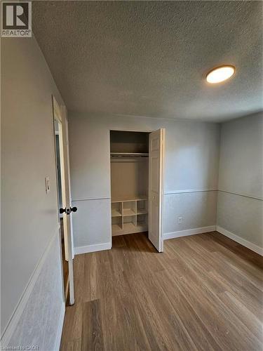 Wood-finish flooring, half-wall molding, and a built-in closet with shelving and bi-fold doors - 99 Cluthe Crescent, Kitchener, ON 