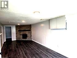 Stone-clad fireplace feature with a dark mantel, dark wood-finish flooring, and recessed ceiling lighting - 