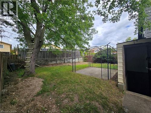 Expansive backyard featuring a mature tree, privacy fencing, a paved patio area, and a metal pergola frame - 99 Cluthe Crescent, Kitchener, ON 