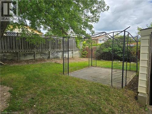 Lawn area with mature tree, wood fencing with lattice detail, and a paved patio area - 99 Cluthe Crescent, Kitchener, ON 