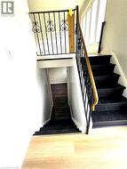 Black finished staircase with ornate black metal railing and wood-finish handrail - 
