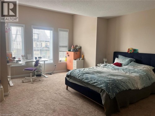 Expansive room featuring multiple windows, neutral wall tones, and textured carpeting - 298 Buttonbush Street, Waterloo, ON 