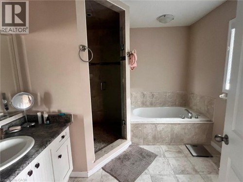 Built-in bathtub with tiled surround, glass-enclosed shower, single vanity with integrated sink, and tiled flooring - 298 Buttonbush Street, Waterloo, ON 