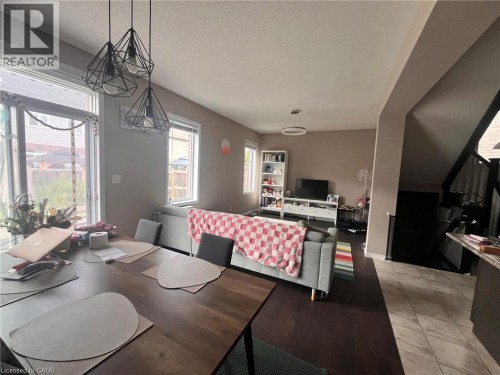 Open-concept living space with dark wood-finish flooring, multiple windows, and geometric pendant lighting - 298 Buttonbush Street, Waterloo, ON 