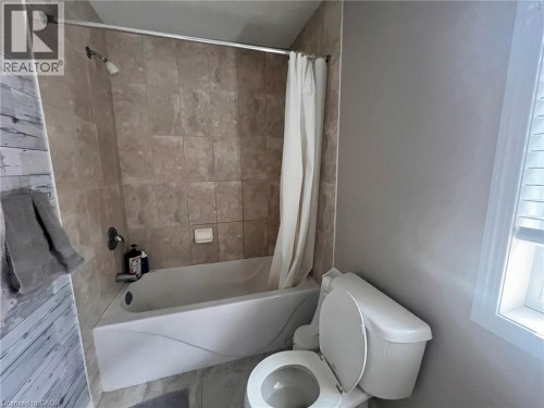 Bathtub with a shower, tiled shower surround, and a toilet - 298 Buttonbush Street, Waterloo, ON 