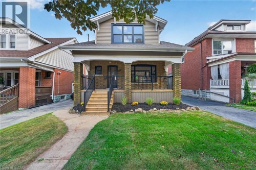 Brick and siding exterior with a covered porch featuring black railings - 229 Park Row S, Hamilton, ON 