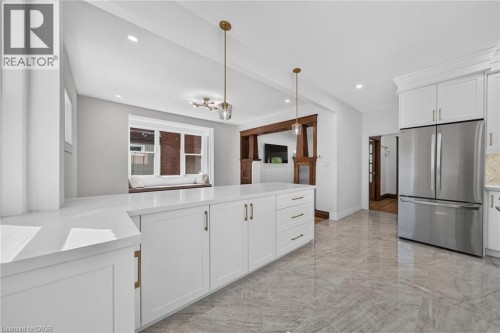 Expansive kitchen island with white cabinetry, gold-tone hardware, and light-toned countertops - 229 Park Row S, Hamilton, ON 