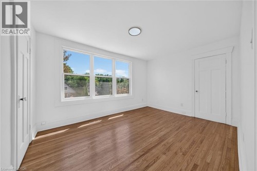 Hardwood flooring, triple-pane window, flush-mount ceiling light, paneled interior doors, and white trim - 229 Park Row S, Hamilton, ON 