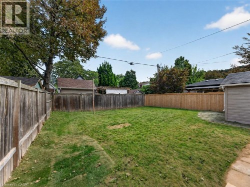 Expansive backyard with a manicured lawn, established perimeter fencing, and a detached auxiliary structure - 229 Park Row S, Hamilton, ON 
