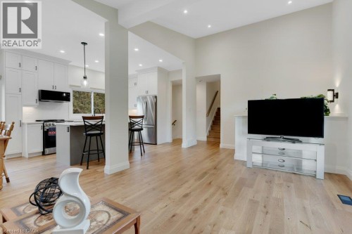 Spacious open-concept living area featuring light wood-finish flooring, recessed lighting, and a modern kitchen with white cabinetry and stainless steel appliances - 196 Abraham Street, Cambridge, ON 